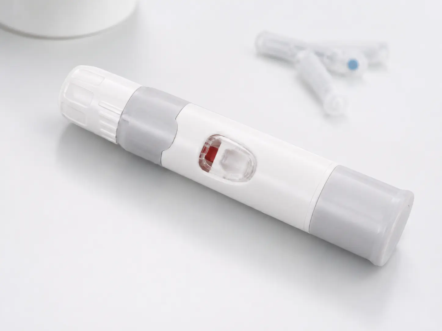 White reusable lancing device with depth adjustment and red status indicator